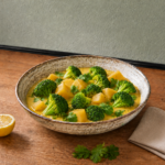 Cremiges Brokkoli-Curry in rustikaler Schüssel mit Sesam, Zitrone und Koriander auf Holzarbeitsplatte