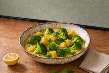 Cremiges Brokkoli-Curry in rustikaler Schüssel mit Sesam, Zitrone und Koriander auf Holzarbeitsplatte